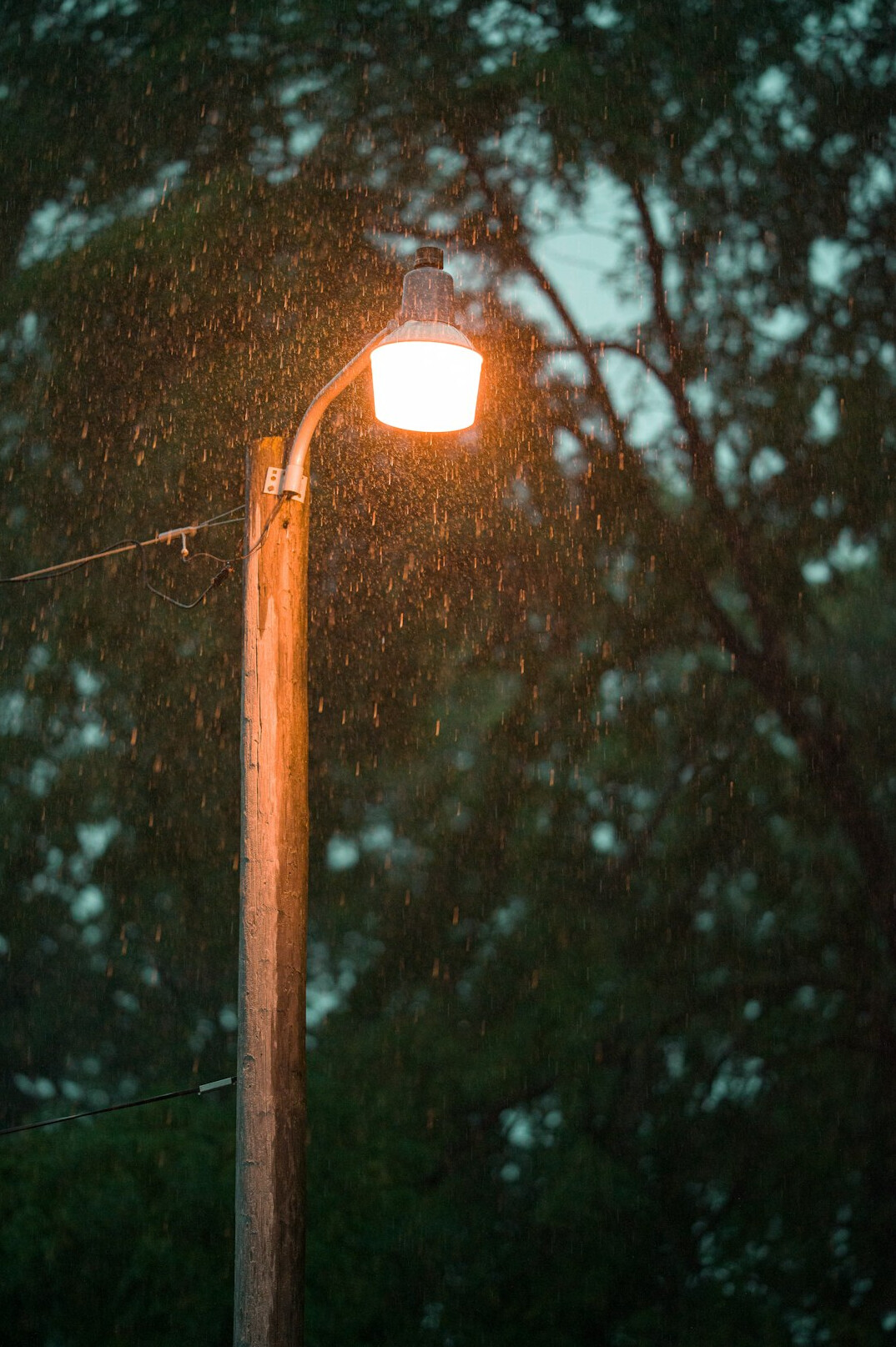 Calle empedrada bajo la lluvia con el reflejo de un farol nocturno